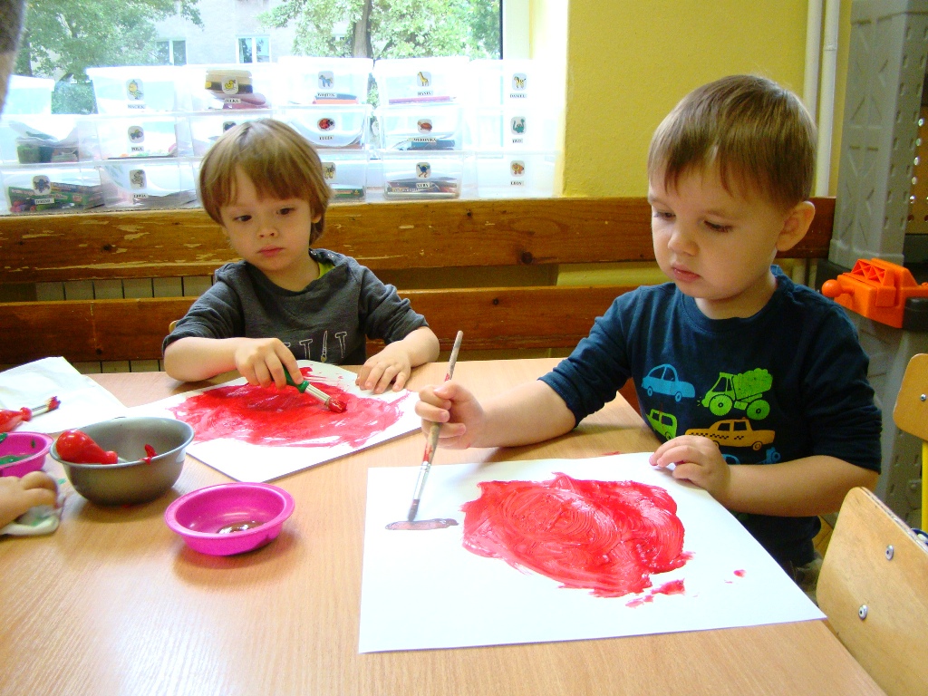 chłopcy malują farbami czerwone jabłka