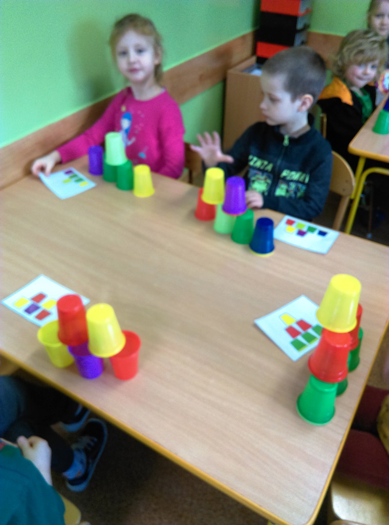 dzieci układają przy stolikach wzory z kubeczków