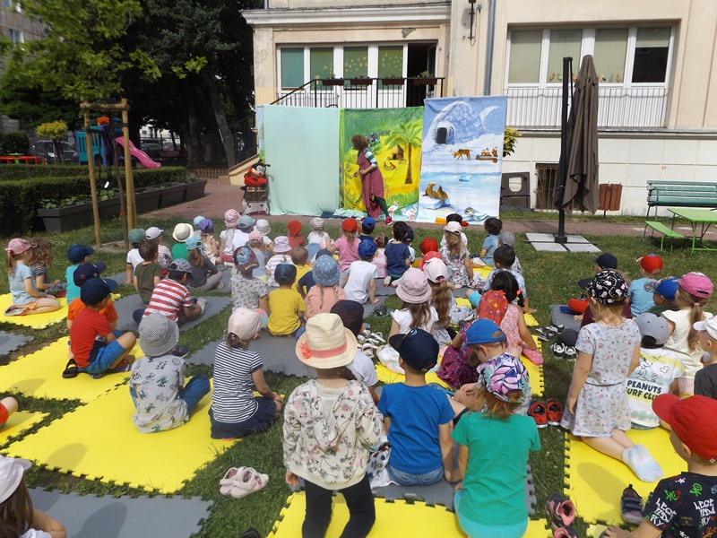 dzieci oglądaja przedstawienie teatralne w ogrodzie