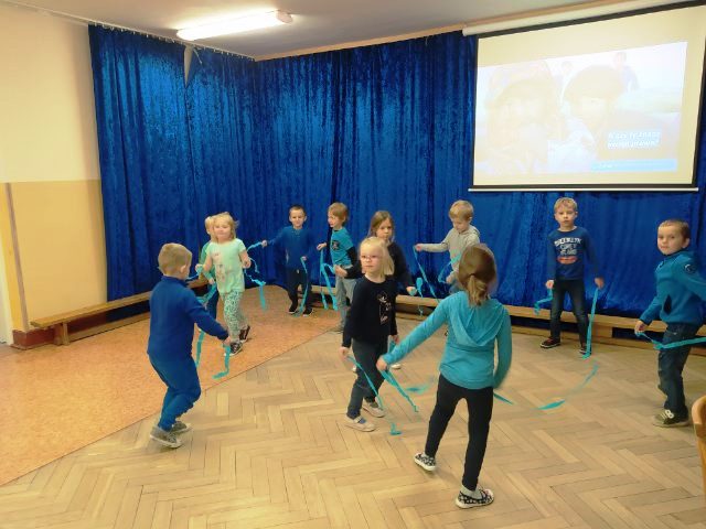 dzieci tańczą trzymając błękitne wstążki