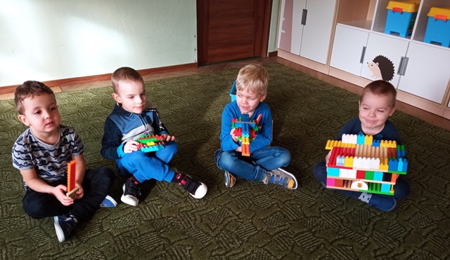 chłopcy siedzą na dywanie z budowlami z klocków
